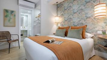 Un dormitorio con cama, una silla, una mesita de noche, aire acondicionado instalado en la pared y un papel tapiz con motivos naturales.