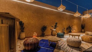 A cozy courtyard with a wooden door, potted plants, hanging wicker lamps, and a blue rug. - L'Emeraude de la Médina - Eleganza e Comfort nel Cuore di Marrakech (Medina)