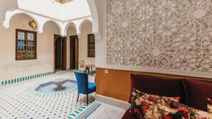 An interior with a fountain, blue chairs, a patterned wall, and a high ceiling. - L'Emeraude de la Médina - Eleganza e Comfort nel Cuore di Marrakech (Medina)
