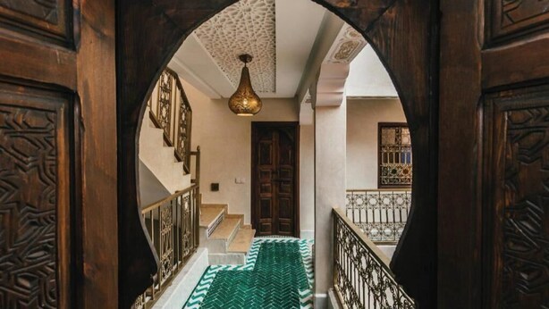 A wooden archway leading to a staircase with a patterned carpet and a hanging light fixture. - L'Emeraude de la Médina - Eleganza e Comfort nel Cuore di Marrakech (Medina)