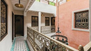 A corridor with ornate metal railings, a patterned floor, and a hanging light fixture. - L'Emeraude de la Médina - Eleganza e Comfort nel Cuore di Marrakech (Medina)