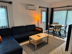 Ein Wohnzimmer mit Sofa, Couchtisch und einem Essbereich mit Stühlen.
