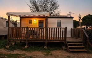 A single-story mobile home with a wooden deck, a covered porch, and a satellite dish. - Mobilhome 4 Pers. near beaches + pool (Port-la-Nouvelle)