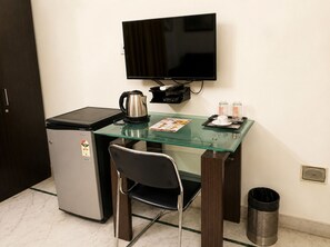 A compact kitchenette with a coffee maker, a small refrigerator, and a flat-screen TV mounted on the wall. - Next Generation Guest House (Bidhannagar)