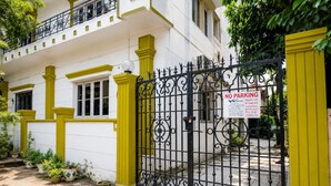 A gated property with a 'NO PARKING' sign, a white building with yellow trim, and potted plants in the foreground. - Next Generation Guest House (Bidhannagar)