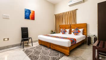 Une chambre d’hôtel avec un lit, une chaise, un bureau, un climatiseur et un tableau au mur.