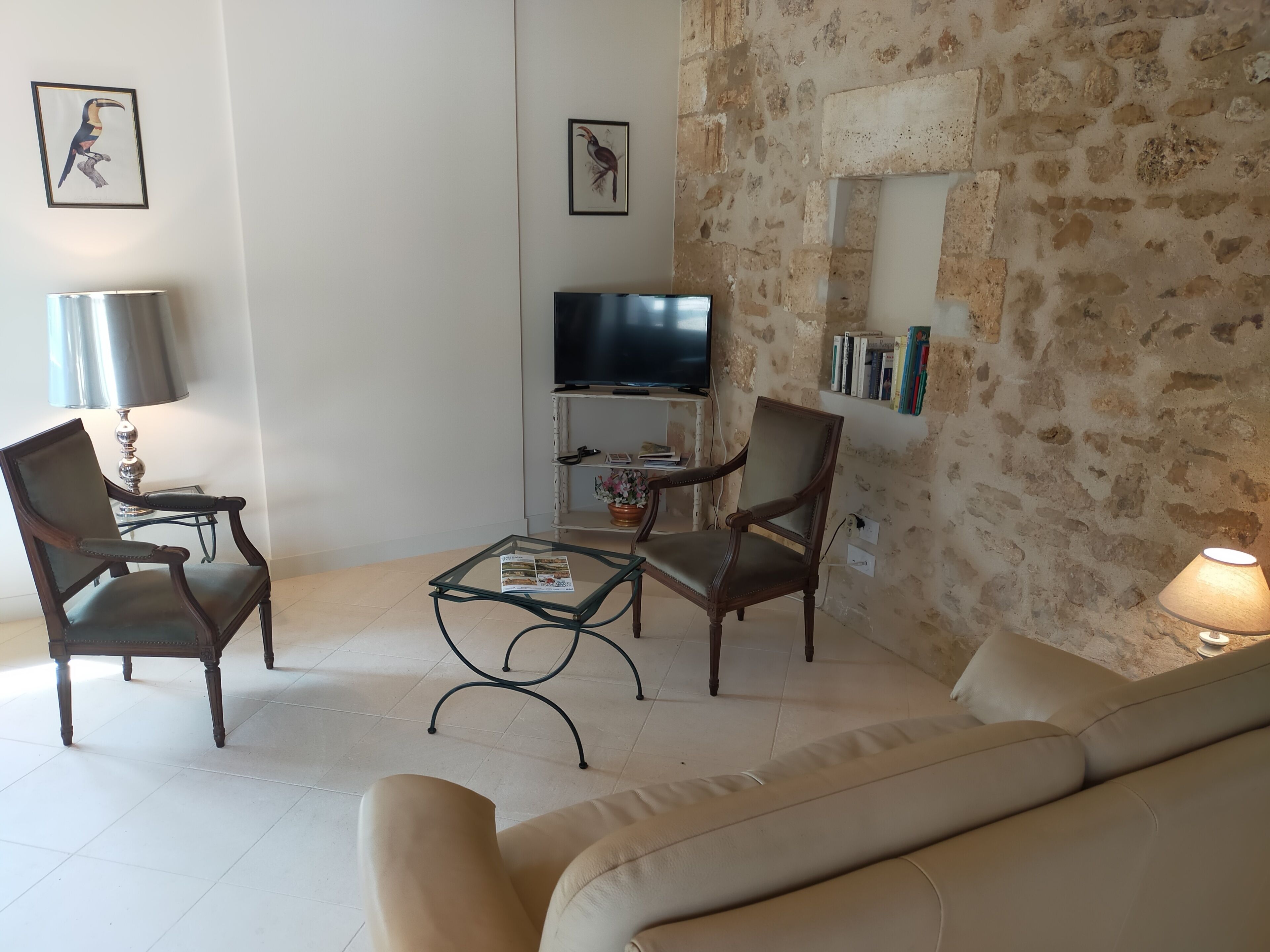 A living room with a sofa, two armchairs, a coffee table, a TV, and a lamp.