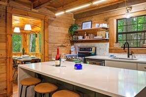 Ein Holzblockhaus-Interieur mit Küche, Essbereich und großen Fenstern.