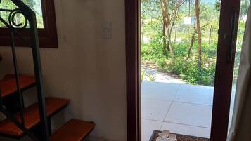 A staircase leading to a covered outdoor area with a view of greenery and a tiled floor.