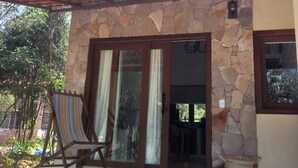 A stone building with a tiled roof, a wooden door, and a patio area with a striped chair. - Colibri Chalet in Vale do Capão, Chapada Diamantina, Bahia, with panoramic views. (Caeté-Açu)