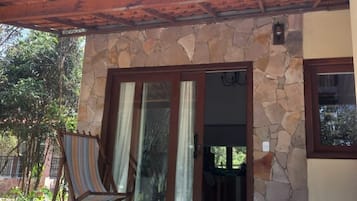 Un edificio de piedra con techo de tejas, una puerta de madera y un patio con una silla a rayas.