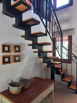 A spiral staircase with wooden steps and black metal railings, leading to an upper floor.