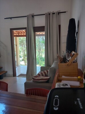 A living room with a sofa, a wooden table, and a view of the outdoors through a door.