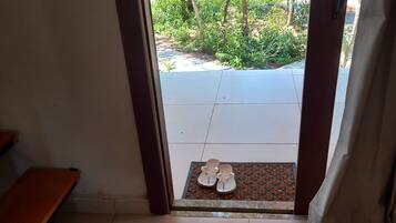 An entrance with a bench, a tiled floor, and a view of a garden through the doorway.