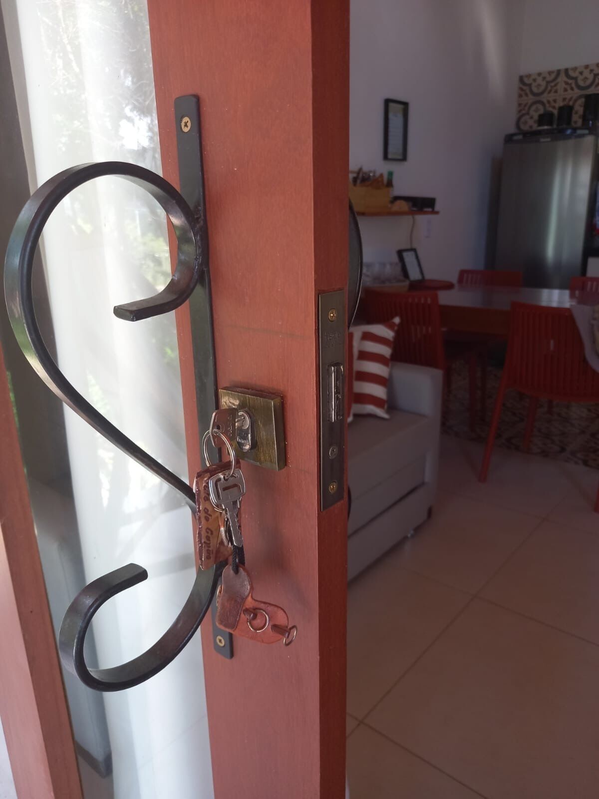 A door with a metal handle, a keyhole, and a keychain with keys.
