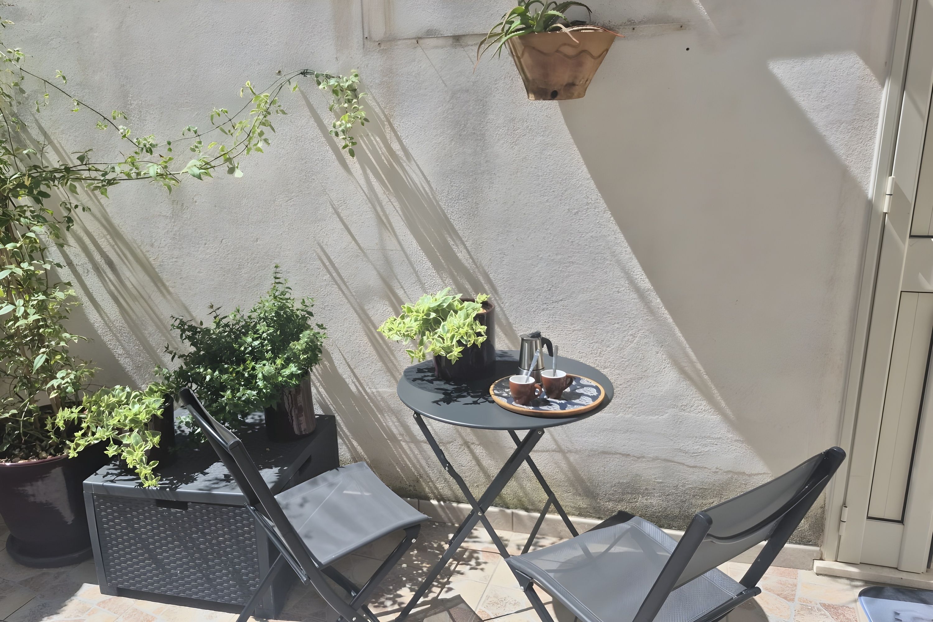 A small outdoor seating area with a table, chairs, and potted plants.