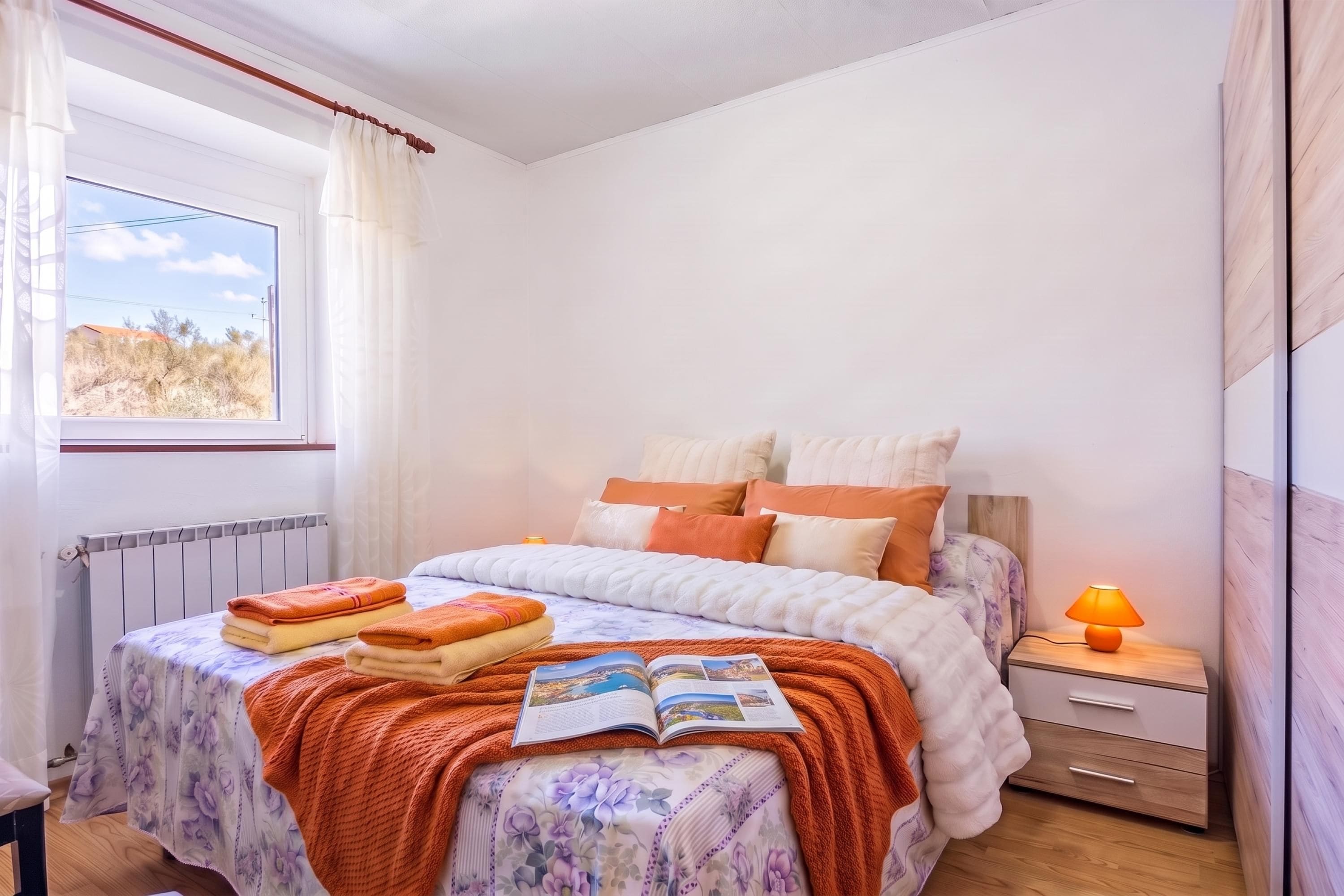 A bedroom with a bed, a nightstand, a lamp, and a window with curtains.