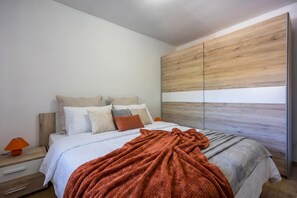 Ein Schlafzimmer mit einem Bett, Kissen, einer Decke, einem Nachttisch und einem Holz-Kopfteil.