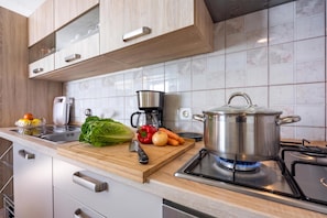 A modern kitchen with a stove, a cutting board with vegetables, a kettle, and a coffee maker. - Rural Apt Lea for 2 /w Terrace (Koper)