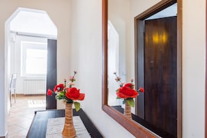 A hallway with a wooden floor, a white doormat, and a mirror reflecting a dark door. - Rural Apt Lea for 2 /w Terrace (Koper)