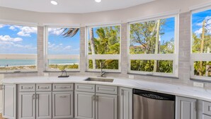 A modern kitchen with a curved island, a built-in dishwasher, and large windows offering a view of the beach. - 180 Degree Ocean Views Direct Access to Holmes Beach (Holmes Beach)
