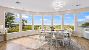 A dining area with a view of the beach, large windows, and a modern ceiling light fixture. - 180 Degree Ocean Views Direct Access to Holmes Beach (Holmes Beach)