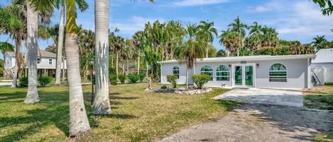 A single-story building with a white exterior, surrounded by palm trees and a well-maintained lawn.