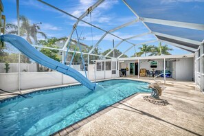 A swimming pool with a blue slide, a covered patio area, and a stone sculpture. - Waterfront 3B Free Boat Parking Near Downtown (Fort Myers)
