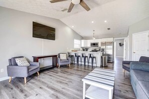 A spacious living area with a modern kitchen, a ceiling fan, and a large window. - Duplex w Private Pool Beach Access Prime PCB (Panama City Beach)