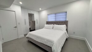 Ein Schlafzimmer mit Bett, Kleiderschrank, Stuhl und Fenster.