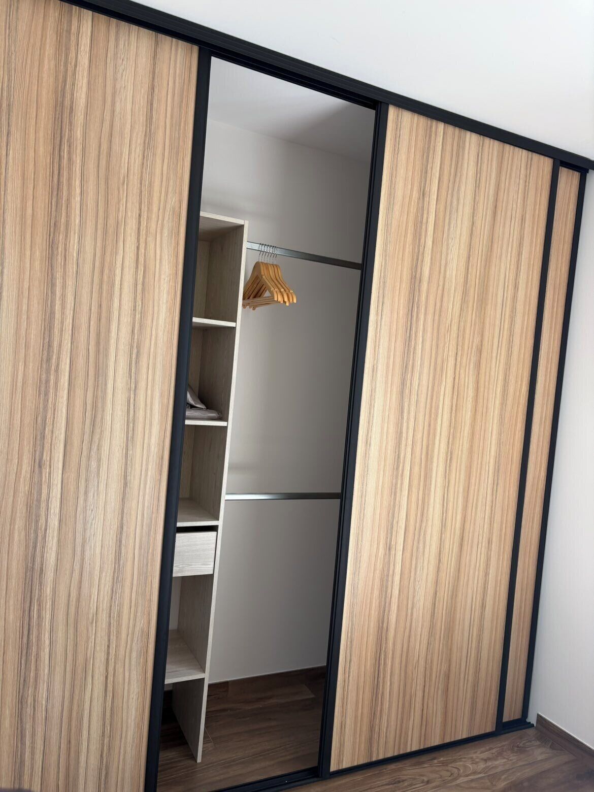 Un placard avec une porte coulissante, une tringle et une étagère.