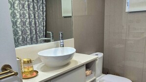 Un bagno moderno con un lavandino bianco, un water e uno specchio grande.