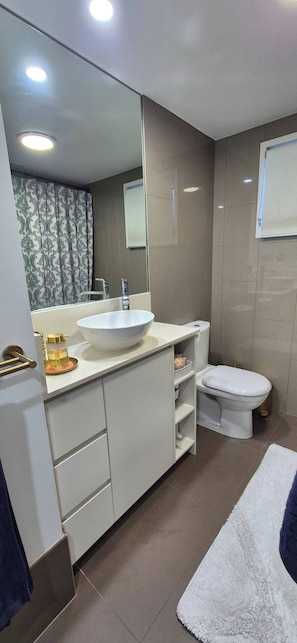 Une salle de bain moderne avec un lavabo blanc, des toilettes et un grand miroir.