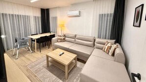 A modern living room with a sofa, coffee table, dining table, and chairs.