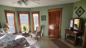 Ein Schlafzimmer mit Bett, Stuhl, Schreibtisch und Tür.