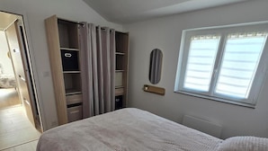 Un dormitorio con cama, armario, espejo y ventana.
