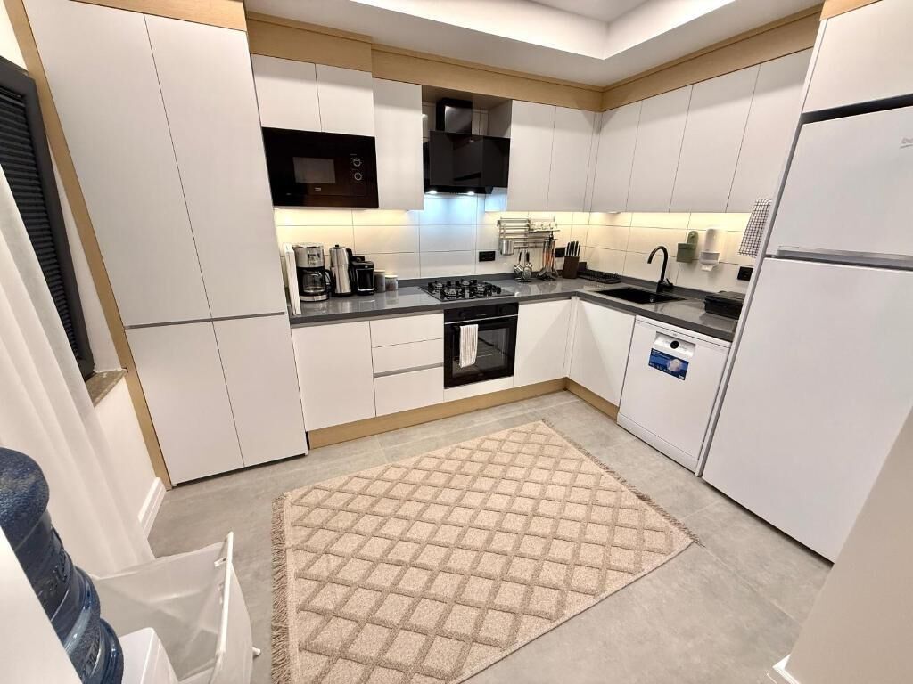 A modern kitchen with white cabinets, a black stove, and a built-in oven.