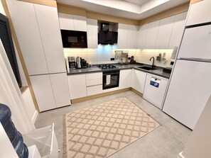 A modern kitchen with white cabinets, a black stove, and a built-in oven.