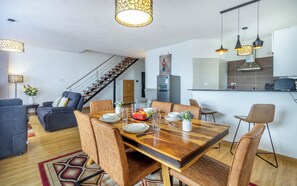 A modern living room with a dining area, staircase, kitchen, and a large mirror. - Luxurious 2 Bedroom Duplex Apartment in Kilimani, Nairobi (Nairobi)