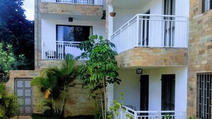 Un immeuble à plusieurs étages doté de balcons, d’un chemin pavé et d’un jardin bien entretenu.