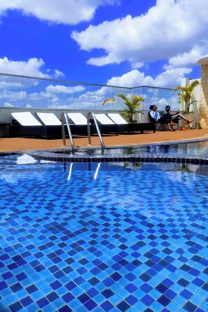 A swimming pool with blue tiles, lounge chairs, and a clear sky. - Luxurious 2 Bedroom Duplex Apartment in Kilimani, Nairobi (Nairobi)