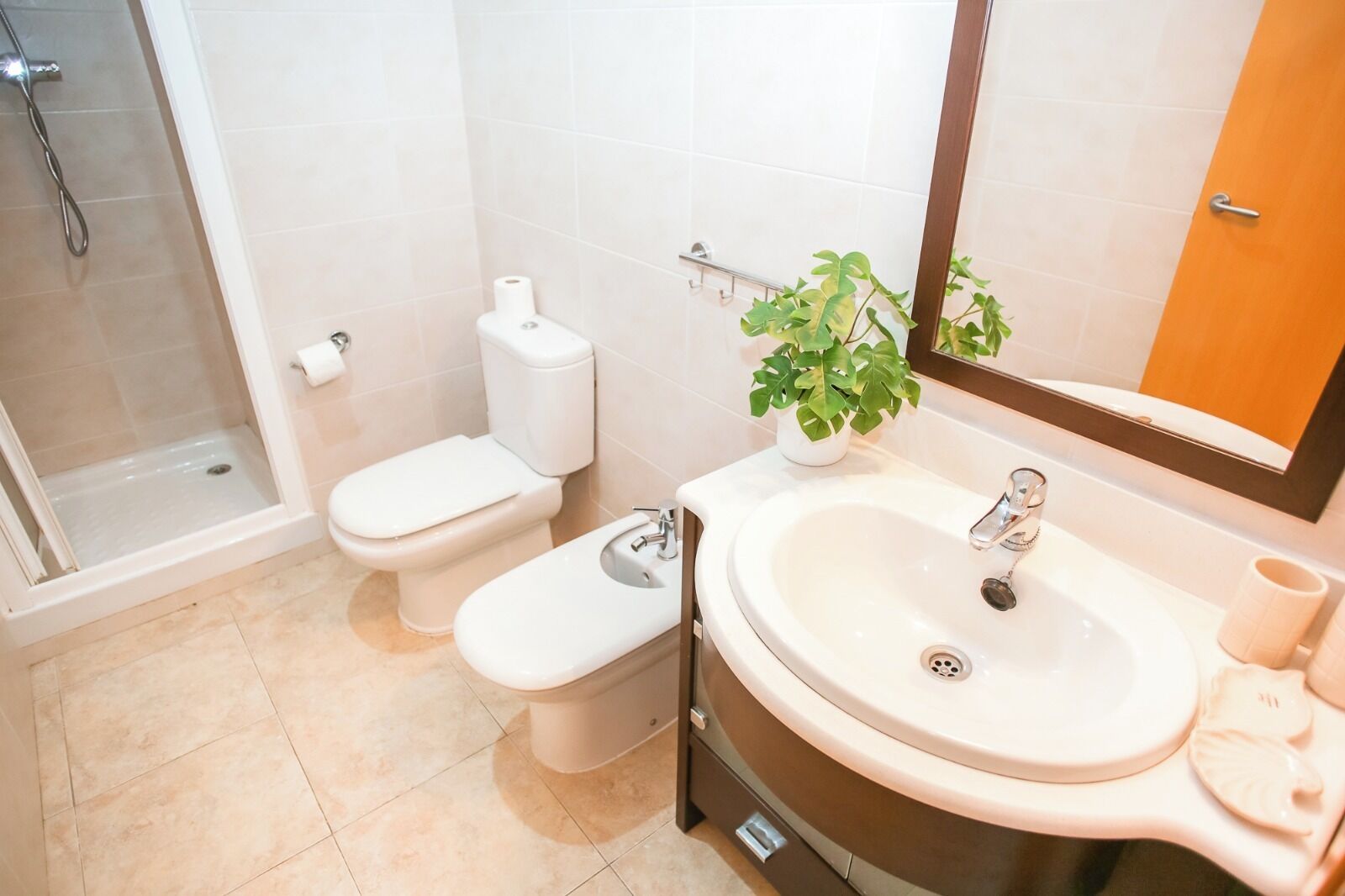 Une salle de bain équipée d’une douche, de toilettes, d’un lavabo et d’un miroir.