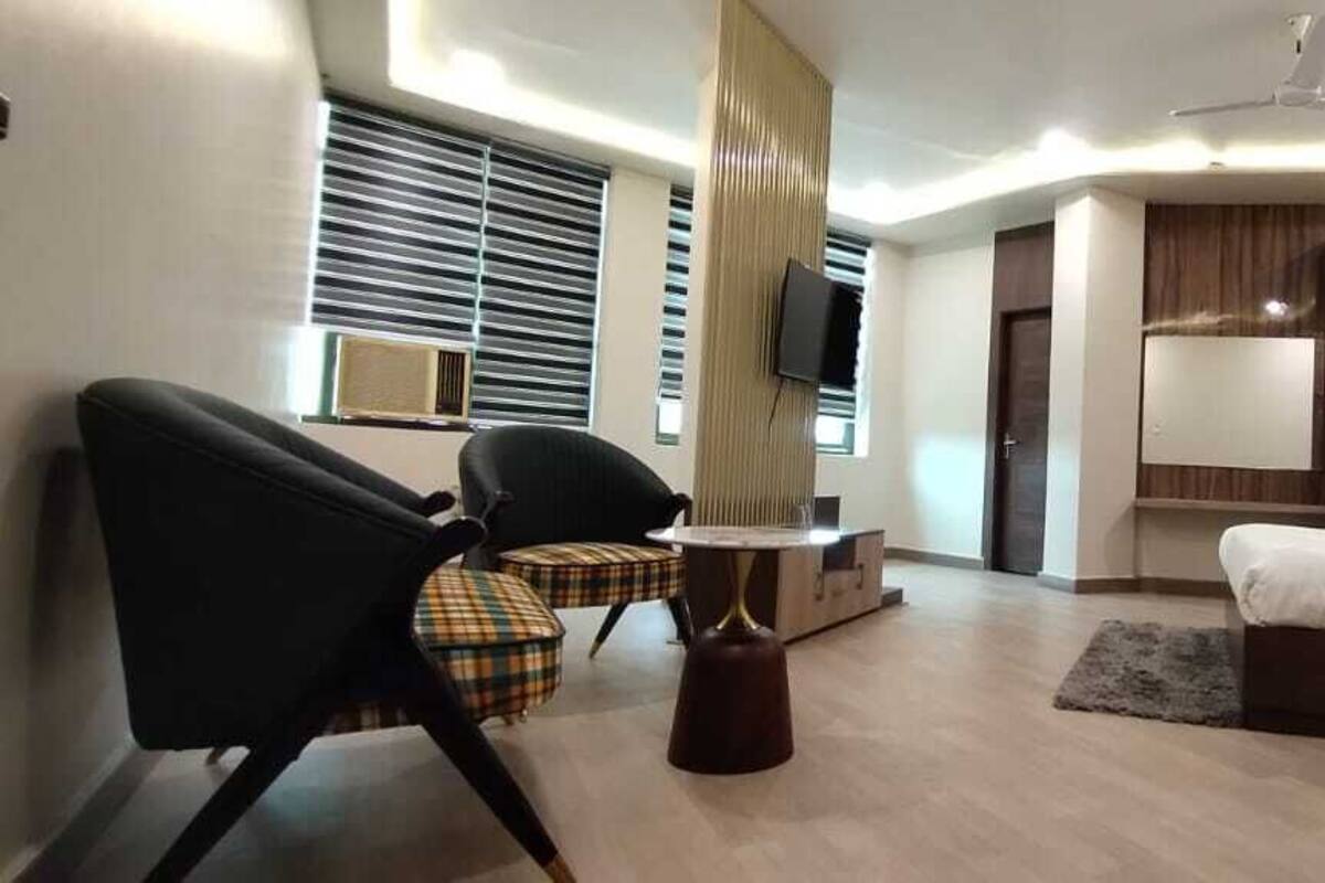 A hotel room with a bed, a desk, a chair, a TV, and a window with blinds.