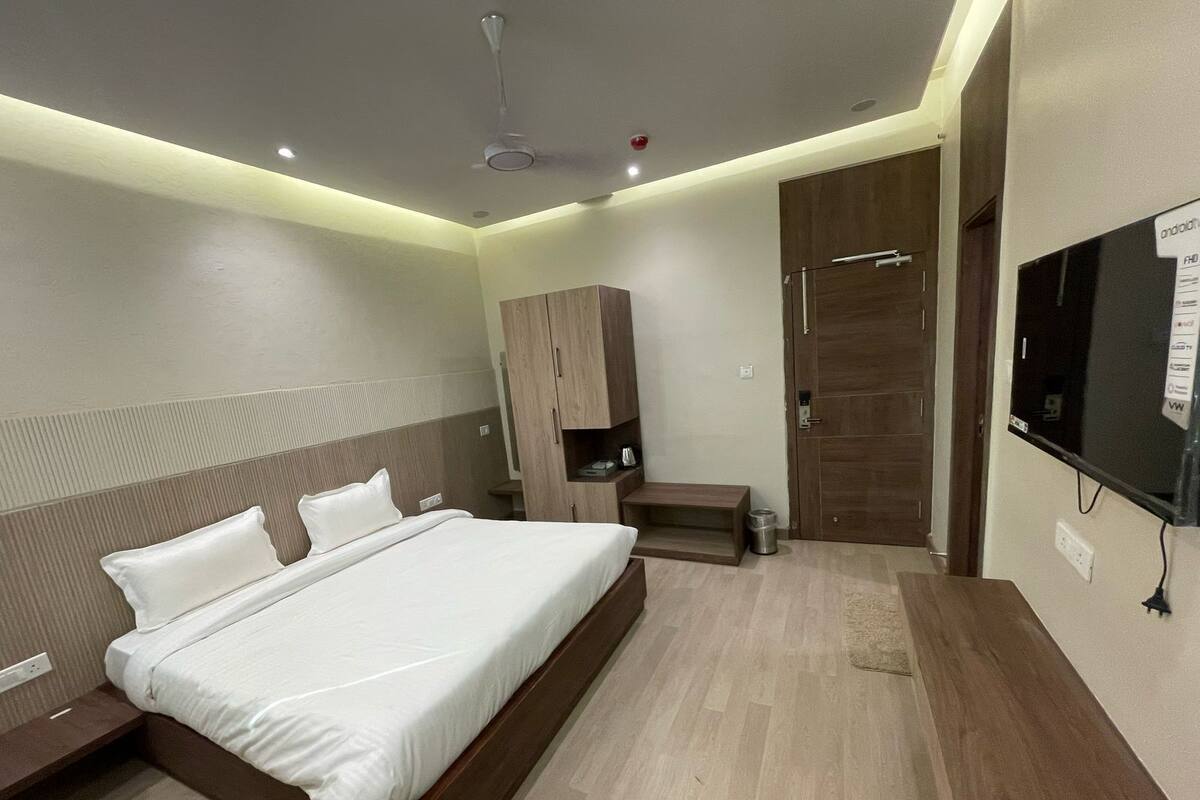 A modern hotel room with a large bed, a wardrobe, a TV, and a shower area.