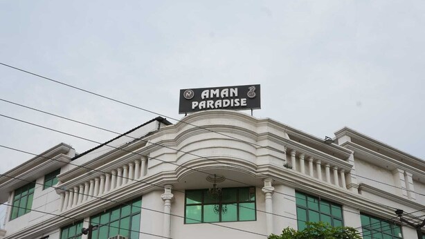 A building with a sign reading 'AMAN PARADISE' and classical architectural features. - Hotel Aman Paradise (Kanpur)