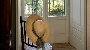 A room with a large window, a wooden chair, and a door. - Masseria Tagliente (Martina Franca)