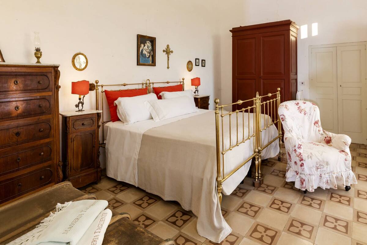 Une chambre à coucher comprenant un lit, une commode, une chaise et une grande armoire en bois.