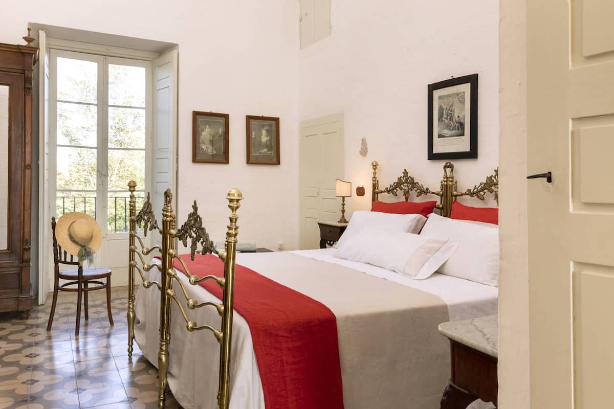 Une pièce avec un lit, une chaise, une fenêtre et une porte.