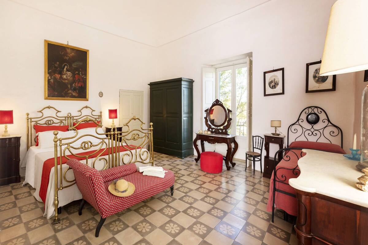 Une pièce comprenant un lit, une chaise, une table, un miroir et une porte.