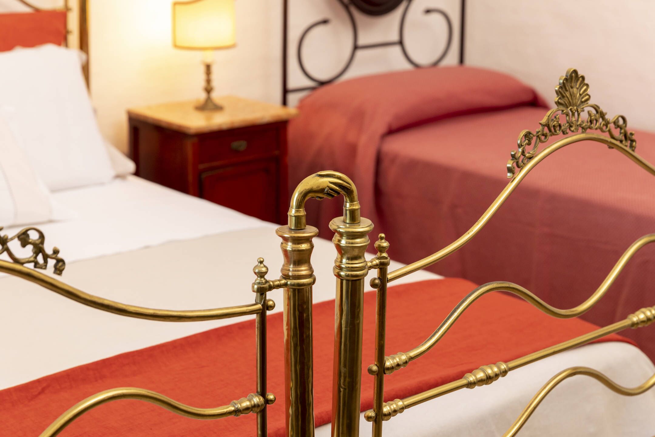 Una cama con cabecera de latón y colcha roja.